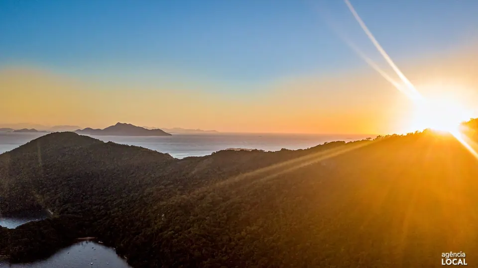 Sol no horizonte sobre os morros cobertos de mata da Ilha Grande, com ilhas ao fundo