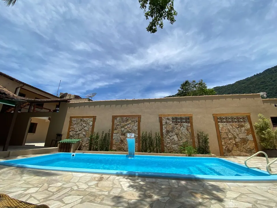 Piscina com cascata e deque de pedra da Pousada Bugio, com o morro coberto de mata ao fundo - pousada em Ilha Grande